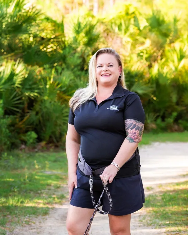 A sitter in a navy polo walking on a shaded Palm Coast trail.